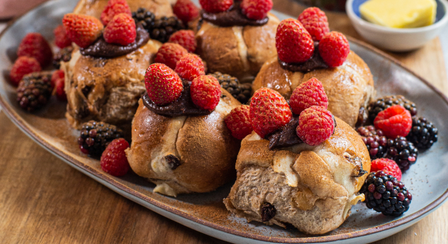 Hot Cross Buns dressed with chocolate spread and mixed berries and served with butter and a bowl of strawberries 